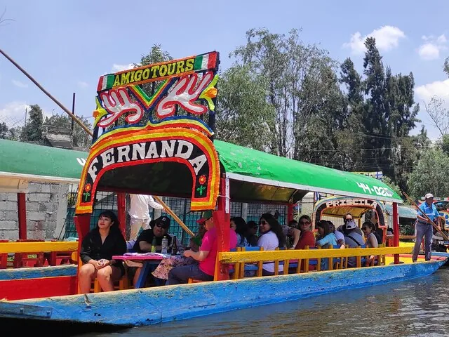 Bunte Trajineras voller Passagiere auf einem belebten Kanal in Xochimilco.