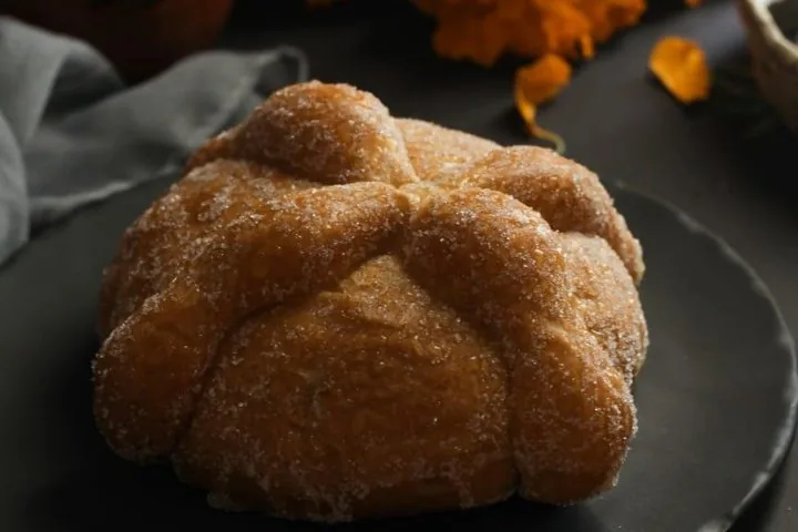 Nahaufnahme eines traditionellen mexikanischen Pan de muerto, der mit Zucker bestäubt ist.