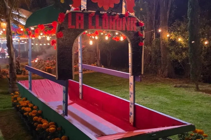 Una pequeña barca decorativa adornada para un evento de 'La Llorona' en un césped.